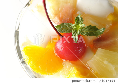 白色背景上裝有牛奶罐、菠蘿、芒果、白桃、櫻桃、橙子等的水果潘趣酒的鳥瞰圖 81047454