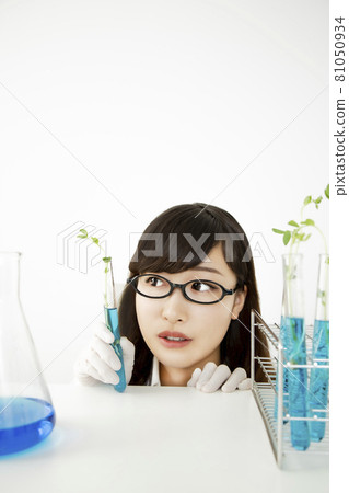 A close-up of the face of a young woman staring at a sample with a smile on her side in a test tube and flask in the laboratory. A close-up of the face of a young woman staring at a sample with a smile on her side in a test tube and flask in the laboratory. 81050934