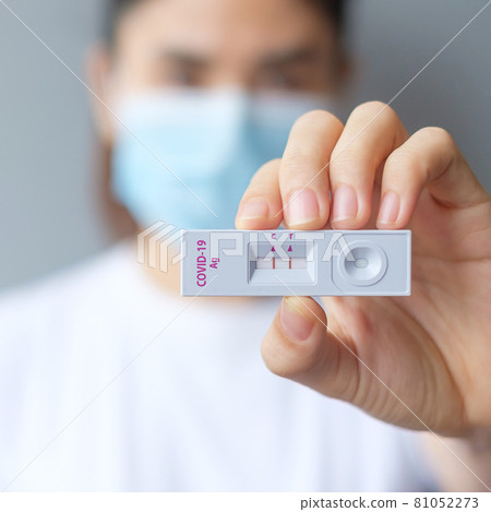 woman holding Rapid Antigen Test kit with Positive result during swab COVID-19 testing. Coronavirus Self nasal or Home test, Lockdown and Home Isolation concept 81052273