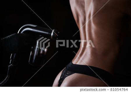 The master sprays tinting paint on the woman's body. Instant tanning procedure The master sprays tinting paint on the woman's body. Instant tanning procedure 81054764