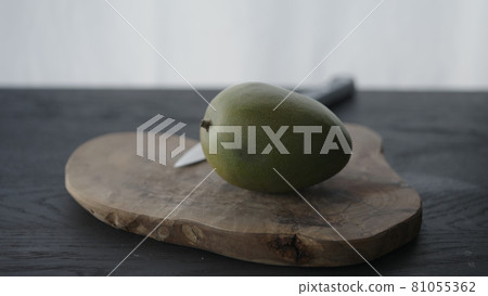 Whole bad mango in halves on olive wood board 81055362