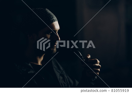 Man smoking a pipe on dark background. Back lit profile portrait. Man smoking a pipe on dark background. Back lit profile portrait. 81055919