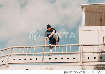 Young sporty guy doing parkour at the city street. 81056553