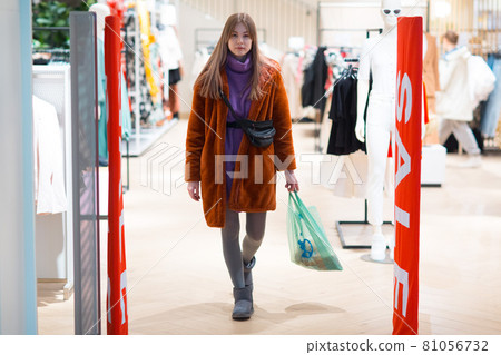 Young woman goes through a security anti-theft framework in a store. Young woman goes through a security anti-theft framework in a store. 81056732