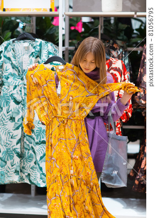 Young woman with shopping bag chooses clothes in store 81056795