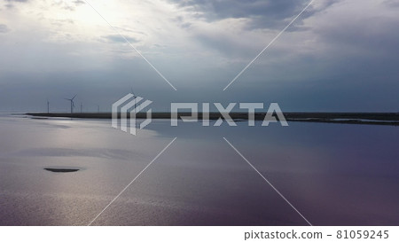 A wind farm on the shores of a pink lake. Evening time. Aerial view. A wind farm on the shores of a pink lake. Evening time. Aerial view. 81059245