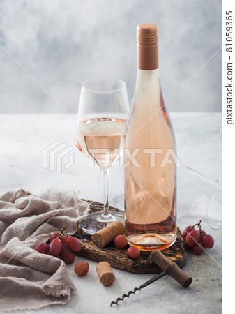 Glass and bottle of rose pink homemade wine with corks, corkscrew and grapes on wooden board Glass and bottle of rose pink homemade wine with corks, corkscrew and grapes on wooden board 81059365