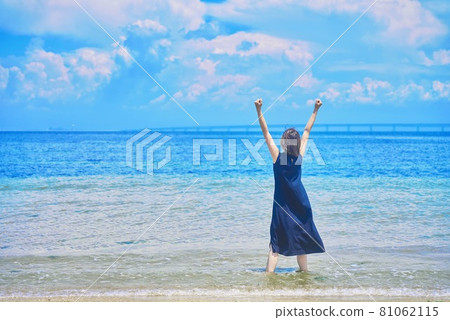 A woman standing on the beach 81062115