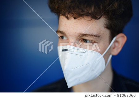 Headshot portrait of young man with respirator against green background outdoors, coronavirus concept. 81062366