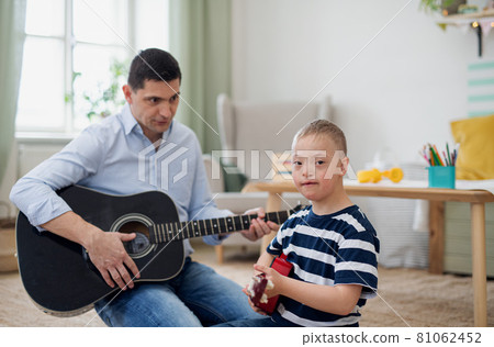 Cheerful down syndrome boy with father playing musical instruments, laughing. 81062452