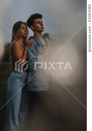 Young couple on a walk in nature at sunset in countryside, standing. Young couple on a walk in nature at sunset in countryside, standing. 81063060