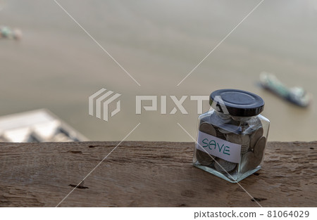 The pile of coins in glass bottle on river background for concept for growth and saving money. The pile of coins in glass bottle on river background for concept for growth and saving money. 81064029