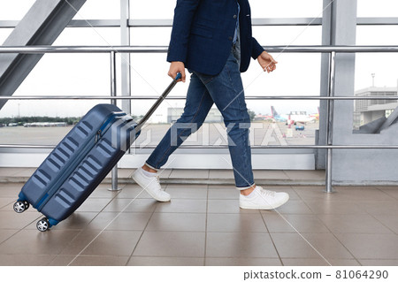 Air Transportation Concept. Unrecognizable man walking with suitcase in airport building 81064290