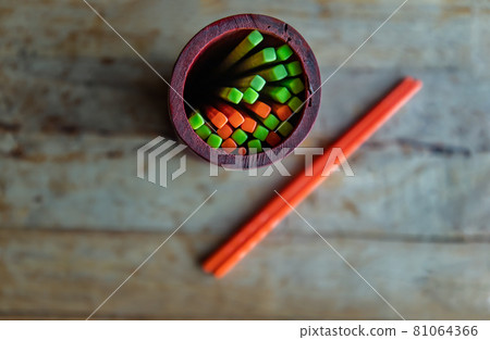 Orange and Green plastic chopsticks grouped in a wooden holder placed on old wooden table in noodle shop. Orange and Green plastic chopsticks grouped in a wooden holder placed on old wooden table in noodle shop. 81064366