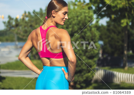 One young slim sportive caucasian woman in bright sportswear standing, looking aside in the park or on city street. One young slim sportive caucasian woman in bright sportswear standing, looking aside in the park or on city street. 81064389