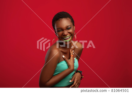 Effective african american young woman laughing on red studio background Effective african american young woman laughing on red studio background 81064501