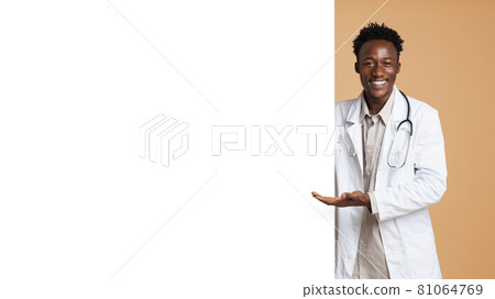 Smiling black male doctor pointing at big blank advertisement board with palm 81064769