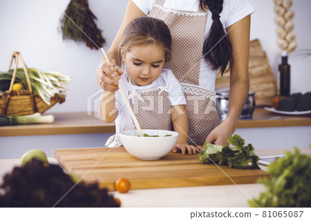 Happy woman and her daughter making healthy vegan salad and snacks for family feasting. Christmas, New year, Thanksgiving, Anniversary, Mothers Day. Healthy meal cooking concept 81065087