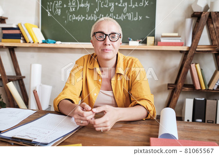 Teacher sitting at desk at school Teacher sitting at desk at school 81065567