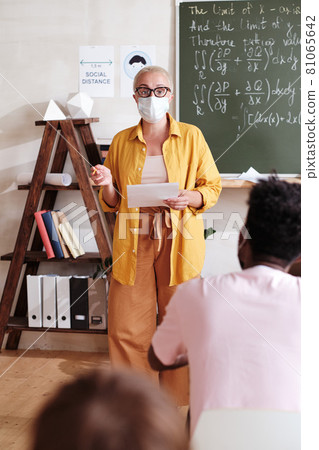 Teacher in mask talking with children 81065642