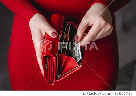 Red wallet in the hands of woman in a red dress with red manicure 81065783