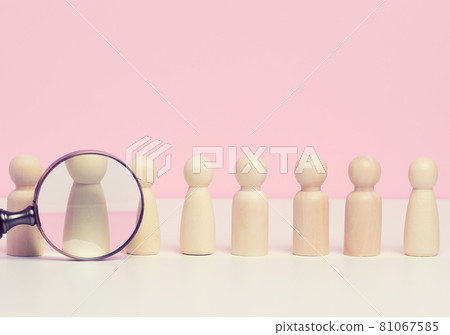 wooden figures of men stand on a pink background and a red plastic magnifying glass. Recruitment concept, search for talented and capable employees wooden figures of men stand on a pink background and a red plastic magnifying glass. Recruitment concept, search for talented and capable employees 81067585