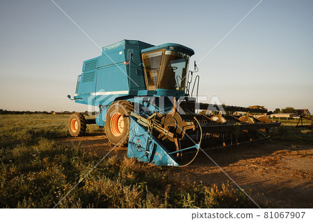 Blue combine harvester agriculture machine harvesting in a field Blue combine harvester agriculture machine harvesting in a field 81067907
