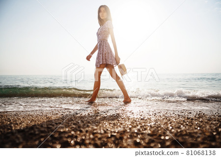 Lonely young woman walks on the seashore at sunset Lonely young woman walks on the seashore at sunset 81068138