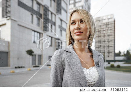 Portrait of young blonde businesswoman in gray suit walking in the city Portrait of young blonde businesswoman in gray suit walking in the city 81068152