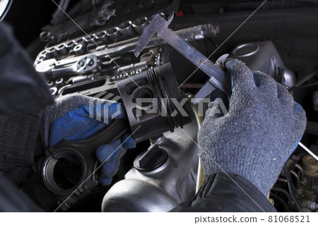 Car engine maintenance. Engine piston system repair. Hands with a mechanic with a caliper measure the size of the piston. Car engine maintenance. Engine piston system repair. Hands with a mechanic with a caliper measure the size of the piston. 81068521