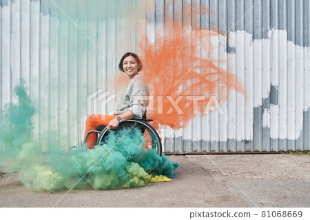 Girl with loss of leg function sitting at the wheelchair and looking at the camera 81068669