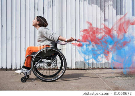 Girl with loss of leg function moving herself at the wheelchair and smiling 81068672