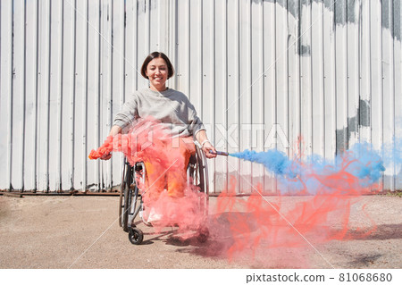 Girl with loss of leg function sitting at wheelchair and playing with bombs with smoke 81068680
