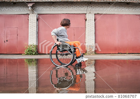 Woman with lower body disability feeling great and moving herself through the puddles 81068707