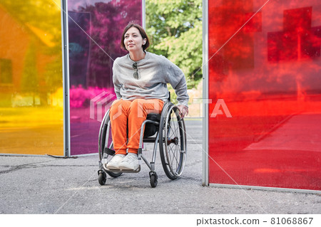 Girl with loss of leg function moving herself with wheelchair while relaxing at nature 81068867