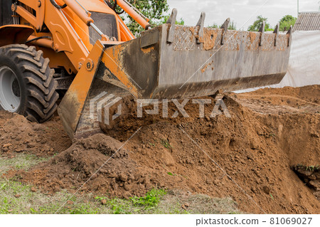 Excavator or bulldozer bucket flattens the ground or road in the industrial zone or construction site 81069027