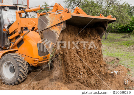 A bucket of a bulldozer fills the trench with earth in an industrial zone. Excavation construction works A bucket of a bulldozer fills the trench with earth in an industrial zone. Excavation construction works 81069029