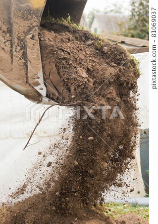 A bulldozer pours out a bucket of land on a construction site close-up. Excavation industrial work A bulldozer pours out a bucket of land on a construction site close-up. Excavation industrial work 81069037
