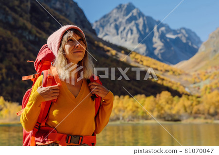 Portrait of hiker happy woman at lake in the autumnal mountains. Mountain lake and tourist Portrait of hiker happy woman at lake in the autumnal mountains. Mountain lake and tourist 81070047