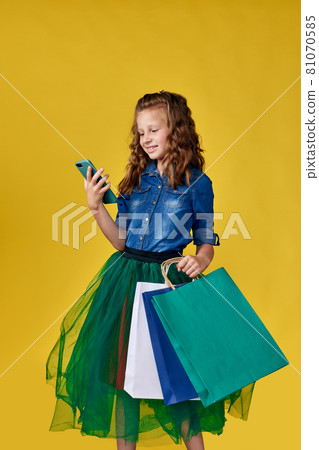 child girl holds shopping bags and using smart phone 81070585