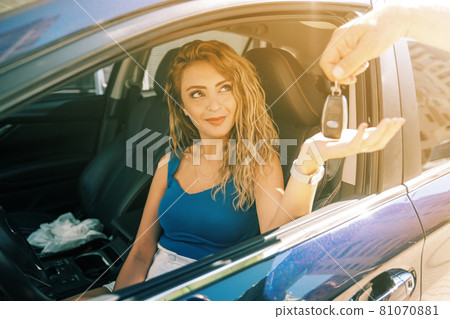 young and beautiful woman take the key from valet to drive her car 81070881