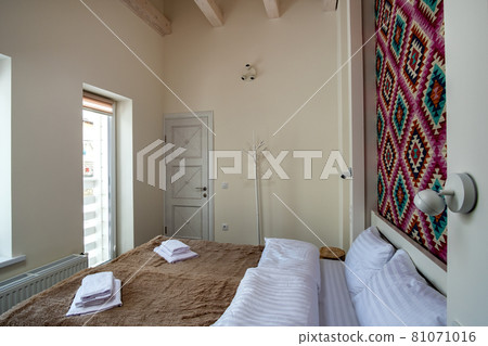 Interior of a spacious hotel bedroom with fresh linen on a big double bed. Cozy contemporary room in a modern house. 81071016