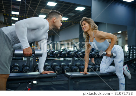 Slim couple doing exercise with dumbbells in gym Slim couple doing exercise with dumbbells in gym 81071758