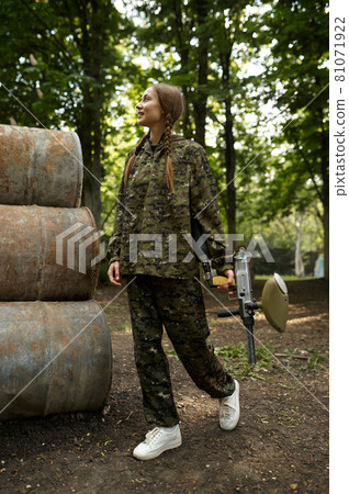 Warrior with paintball gun poses on rusty barrels Warrior with paintball gun poses on rusty barrels 81071922