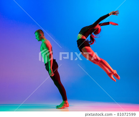 Stylish sportive caucasian couple, male and female dancer dancing contemporary dance on colorful gradient blue pink background in neon light. 81072599