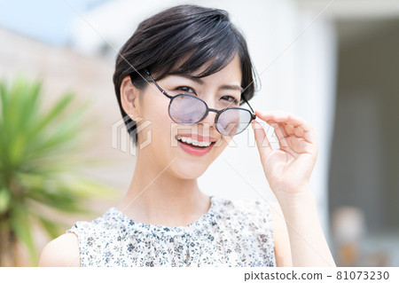 Bust-up portrait of a young woman wearing sunglasses 81073230