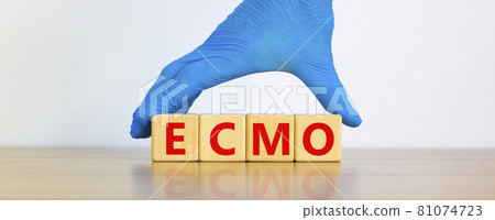 ECMO symbol. Concept words 'ECMO, Extra Corporeal Membrane Oxygenation' on cubes on a beautiful white background. Doctor hand in blue glove. Copy space. Medical, ECMO concept. ECMO symbol. Concept words 'ECMO, Extra Corporeal Membrane Oxygenation' on cubes on a beautiful white background. Doctor hand in blue glove. Copy space. Medical, ECMO concept. 81074723