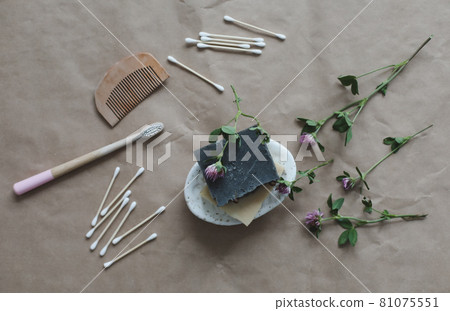 Eco spa friendly products. Handmade natural soap, wooden toothbrushes, cotton swabs and hairbrush on craft paper background top view with copyspace 81075551