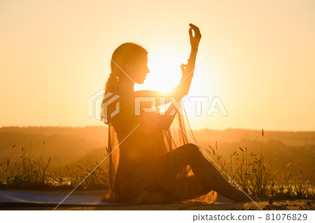 Beautiful female silhouette sit in warm sun 81076829