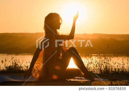 Silhouette of woman doing yoga against warm sun 81076830